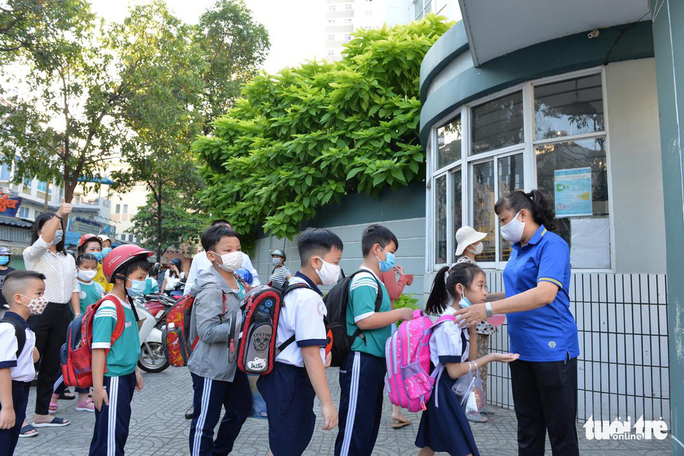 Học sinh Trường tiểu học Nguyễn Văn Trỗi (quận 4, TP.HCM) xếp hàng vào trường sáng 1-3, các em đều đeo khẩu trang, đo thân nhiệt và rửa tay - Ảnh: TỰ TRUNG