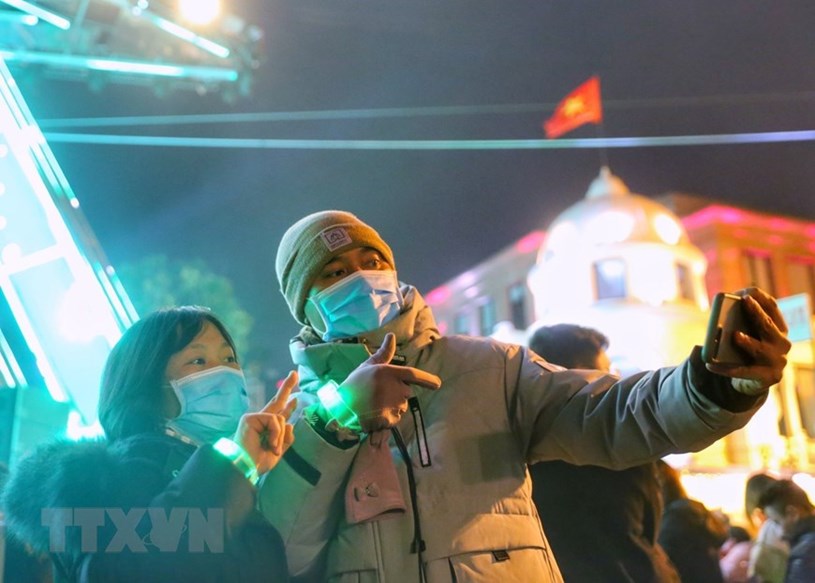 Người dân chụp ảnh lưu niệm chào mừng năm mới tại Quảng trường Cách mạng tháng Tám. (Ảnh: Tuấn Đức/TTXVN)