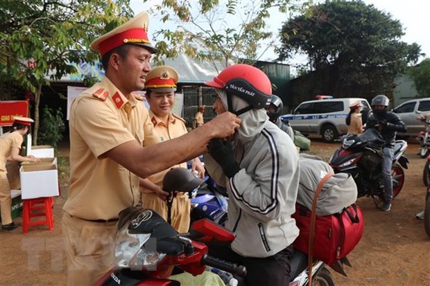 Cảnh s&aacute;t giao th&ocirc;ng Đắk N&ocirc;ng tuy&ecirc;n truyền ph&aacute;p luật về trật tự an to&agrave;n giao th&ocirc;ng, đồng thời đổi mũ bảo hiểm đạt chuẩn cho người d&acirc;n. (Ảnh: TTXVN ph&aacute;t)