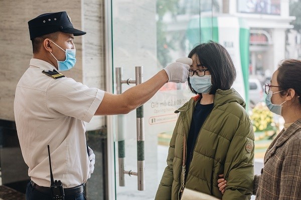 Bảo vệ tiến h&agrave;nh đo th&acirc;n nhiệt cho kh&aacute;ch gh&eacute; thăm trung t&acirc;m thương mại. (Nguồn: Vietnam+)