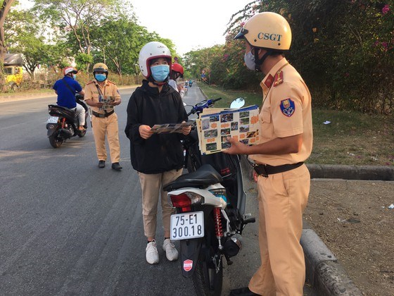 Lực lượng CSGT TPHCM ph&aacute;t tờ rơi tuy&ecirc;n truyền an to&agrave;n giao th&ocirc;ng, ph&ograve;ng chống dịch Covid-19 nhằm n&acirc;ng cao nhận thức của người d&acirc;n. Ảnh: CA cung cấp