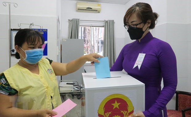 Cử tri l&agrave; th&acirc;n nh&acirc;n người bệnh bỏ phiếu v&agrave;o th&ugrave;ng phiếu lưu động ngay tại ph&ograve;ng bệnh của Bệnh viện Chợ Rẫy. (Ảnh: Đinh Hằng/TTXVN)