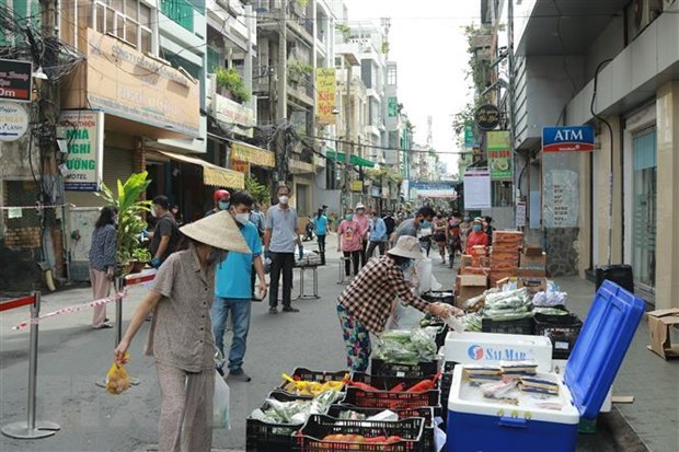 Người d&acirc;n mua h&agrave;ng h&oacute;a thiết yếu tại một Phi&ecirc;n chợ lưu động được tổ chức tại khu phố 3, phường 2, Quận 3, Th&agrave;nh phố Hồ Ch&iacute; Minh. (Ảnh: Quang Ch&acirc;u/TTXVN)