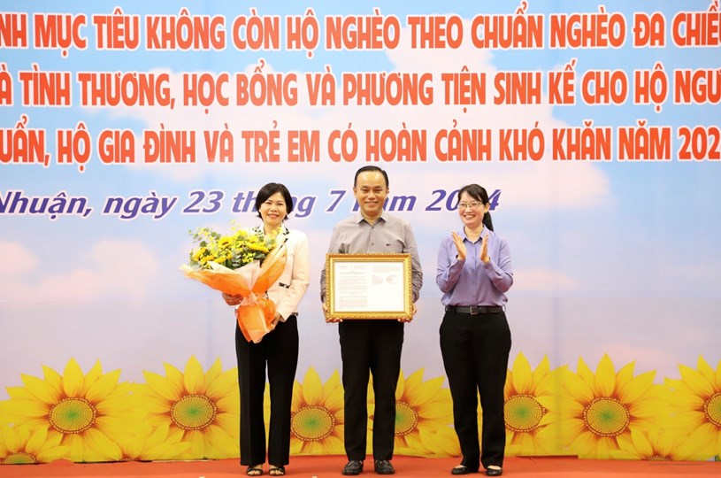 Chủ tịch UBND quận Ph&uacute; Nhuận (giữa) nhận quyết định c&ocirc;ng nhận ho&agrave;n th&agrave;nh mục ti&ecirc;u kh&ocirc;ng c&ograve;n hộ ngh&egrave;o theo chuẩn ngh&egrave;o đa chiều của th&agrave;nh phố giai đoạn 2021-2025 &nbsp;