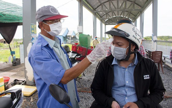 Trước khi l&ecirc;n ph&agrave;, h&agrave;nh kh&aacute;ch phải được kiểm tra đo th&acirc;n nhiệt. Ảnh: Đ&Igrave;NH DƯ