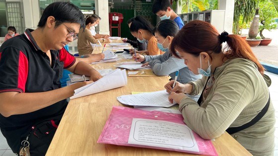 Phụ huynh l&agrave;m thủ tục cho con nhập học lớp 6 Trường THCS Ch&aacute;nh Hưng, quận 8, TPHCM. Ảnh: CAO THĂNG