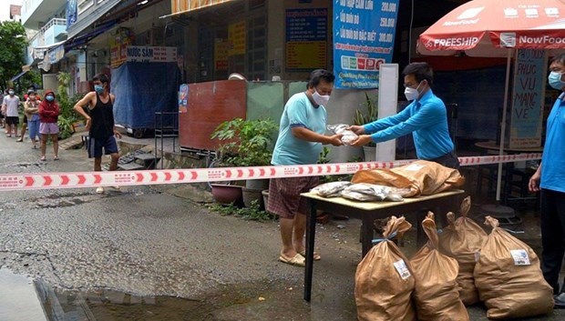 Đại diện Li&ecirc;n đo&agrave;n Lao động quận B&igrave;nh Thạnh trao qu&agrave; cho c&ocirc;ng nh&acirc;n ở trọ, người ngh&egrave;o trong khu phong tỏa. (Ảnh: TTXVN ph&aacute;t)