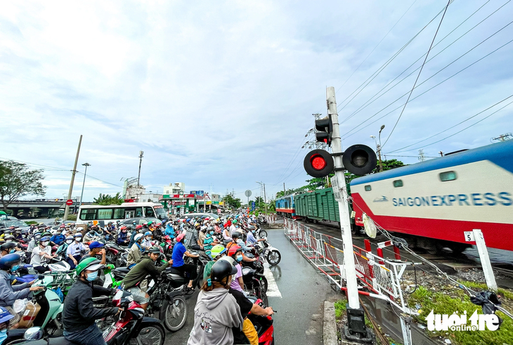 Người d&acirc;n dừng chờ tàu chạy ngang tại đường sắt khu vực TP Thủ Đức - Ảnh: L&Ecirc; PHAN