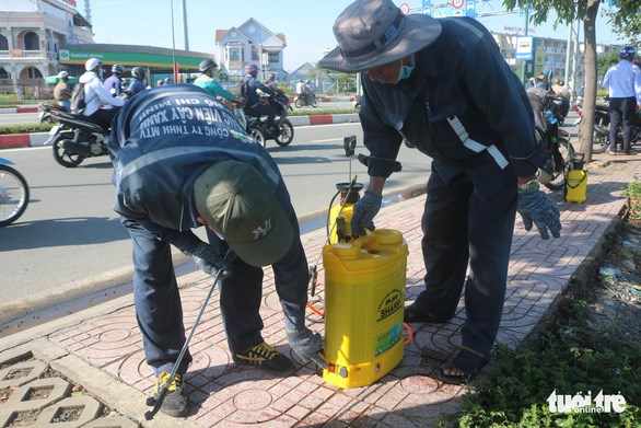 C&ocirc;ng nh&acirc;n pha thuốc sinh học để phun l&ecirc;n c&acirc;y tr&ecirc;n tuyến đường Phạm Văn Đồng - Ảnh: THU HIẾN