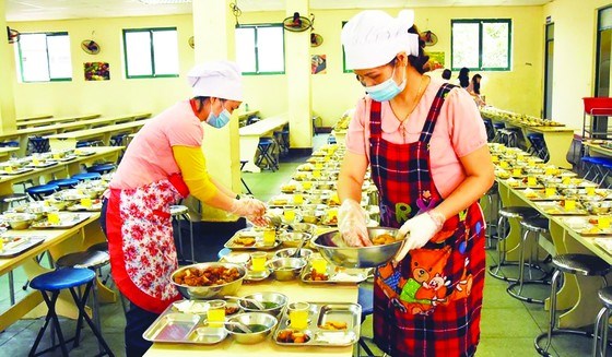 Bảo mẫu tại bếp ăn tập thể một trường học tr&ecirc;n địa b&agrave;n TPHCM chuẩn bị suất ăn trưa cho học sinh. Ảnh: TH&Agrave;NH AN