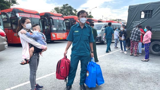 Chiến sĩ dân quân hỗ trợ chị Hồ Thị Hồng Châu đưa hành lý lên xe về quê. Ảnh: VĂN MINH