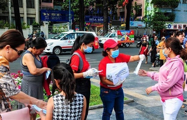 Nh&acirc;n vi&ecirc;n Sở Du lịch Th&agrave;nh phố Hồ Ch&iacute; Minh ph&aacute;t khẩu trang miễn ph&iacute; cho kh&aacute;ch du lịch. (Ảnh: Đinh Hằng/TTXVN)