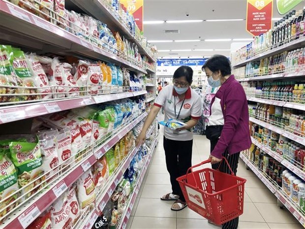 Nhân viên siêu thị Thành phố Hồ Chí Minh giới thiệu hàng tiêu dùng thiết yếu đến khách hàng. (Ảnh: Mỹ Phương/TTXVN)
