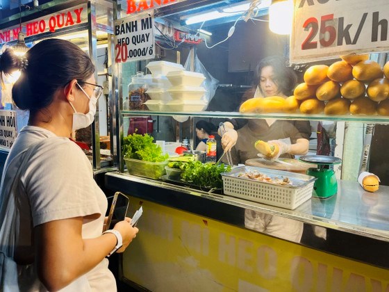 Kh&aacute;ch mua b&aacute;nh m&igrave; tại cửa h&agrave;ng heo quay Tường - Thịnh
