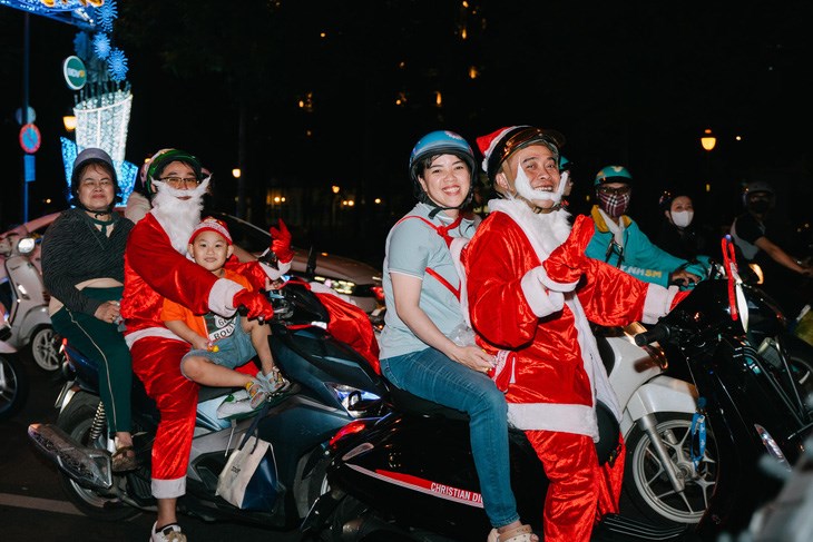 C&aacute;c gia đ&igrave;nh c&ugrave;ng nhau đi dạo phố với trang phục &ocirc;ng gi&agrave; Noel - Ảnh: THANH HIỆP
