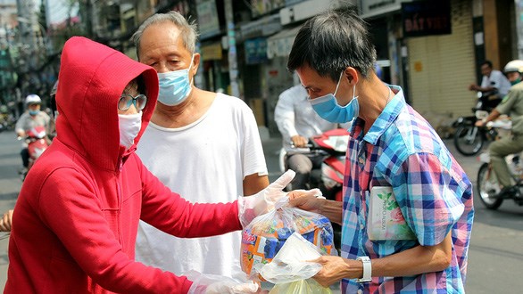 Người b&aacute;n v&eacute; số dạo nhận gi&uacute;p đỡ từ những tấm l&ograve;ng thảo thơm của người d&acirc;n TP. Hồ Ch&iacute; Minh. Ảnh L&yacute; Nguy&ecirc;n/ Tuổi Trẻ.