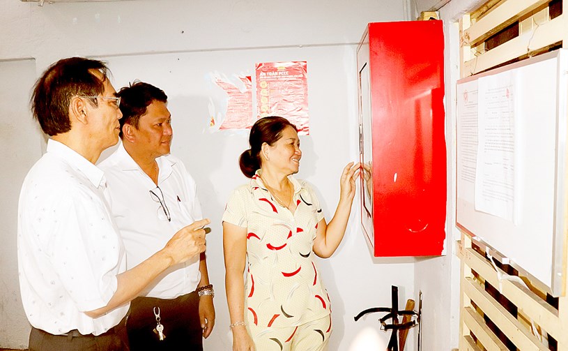 Ông Nguyễn Văn Quang (bìa trái), Bí thư Chi bộ Khu phố 4, phường 14, quận 5 hướng dẫn người dân chung cư tại khu phố sử dụng tủ PCCC. Ảnh: THÁI PHƯƠNG