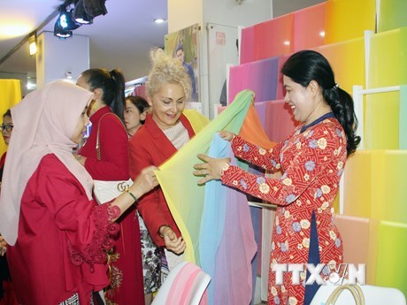 Đại diện các cơ quan ngoại giao trên địa bàn Thành phố Hồ Chí Minh tham quan khu trưng bày sản phẩm lụa may áo dài. (Ảnh: Mỹ Phương/TTXVN)