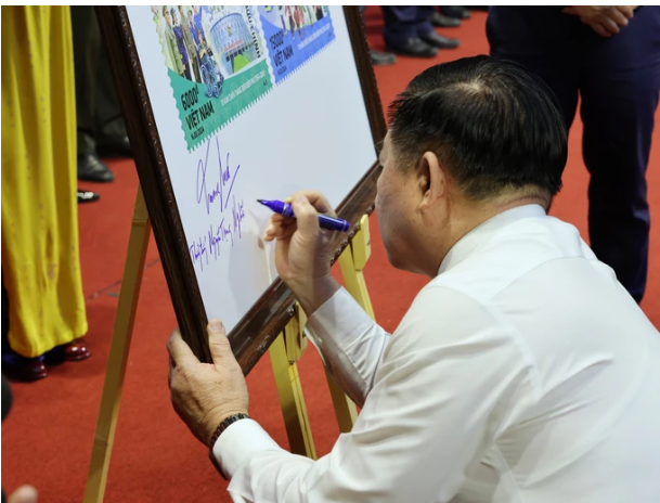 Đồng chí Nguyễn Trọng Nghĩa ký trên bộ ảnh tem đặc biệt. Ảnh: QUANG PHÚC