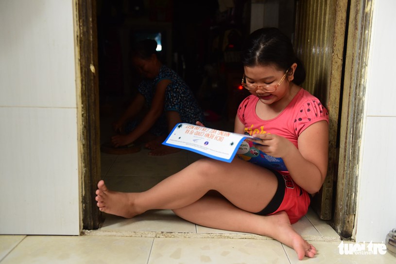 Em Kim Ngọc (10 tuổi) đọc ngay sau khi c&oacute; tờ rơi - Ảnh: QUANG ĐỊNH