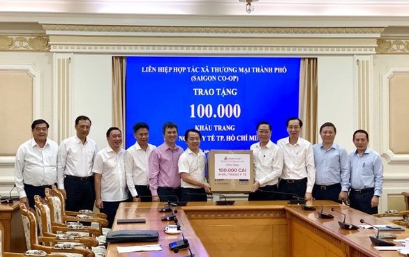 &Ocirc;ng Nguyễn Anh Đức, ph&oacute; tổng gi&aacute;m đốc Saigon Co.o p (thứ 6 từ tr&aacute;i qua), tặng 100.000 khẩu trang y tế tại UBND TP ng&agrave;y 2-3 - Ảnh: TTO